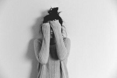 Teenage girl hiding face while standing against white background