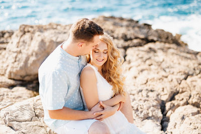 Young couple sitting on rock at beach