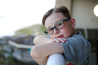 Side view portrait of boy leaning on railing at balcony