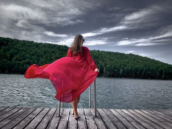 Rear view of woman looking at lake against sky
