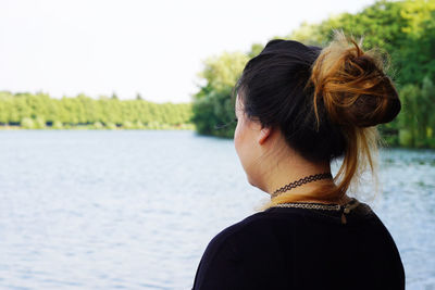 Rear view of young woman standing by lake