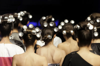 Rear view of women wearing hair curlers at fashion show