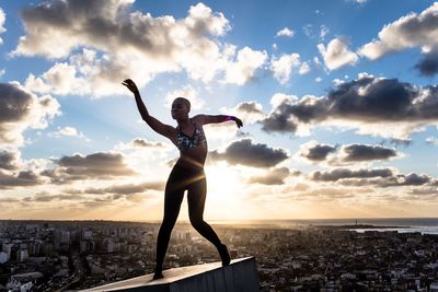 Silhouette of woman standing against sky at sunset