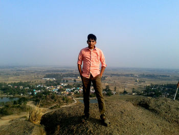 Portrait of man standing on hill against clear sky