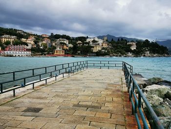 Pier by sea against buildings in city against sky