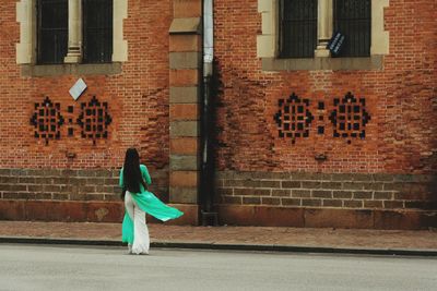 Full length of woman walking on footpath against building