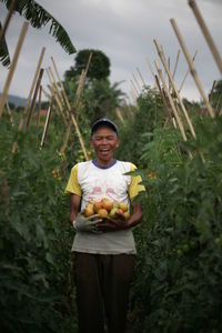 Farmer holding tomatoes while standing at farm