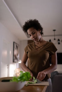 Mixed race woman chopping cucumber for salad