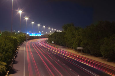 Light trails on road against sky at night