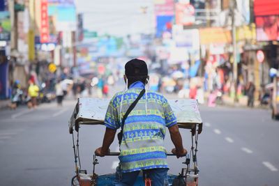 Rear view of man riding bicycle on city street