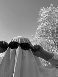 Low section of ghost wearing sunglasses against sky