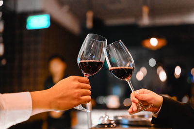 Cropped hands of man and woman toasting wine