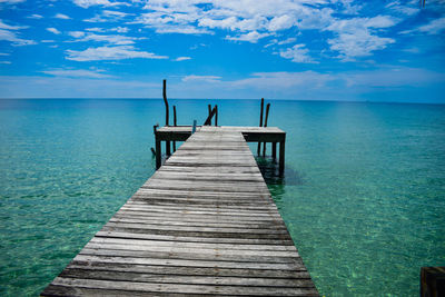Wooden jetty on pier over sea against sky