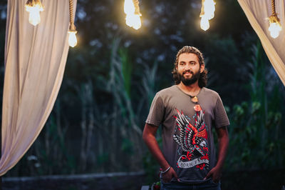 Portrait of young man standing against illuminated lights