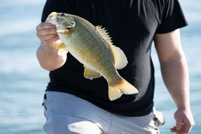 Close up of a man holding a fish by the mouth