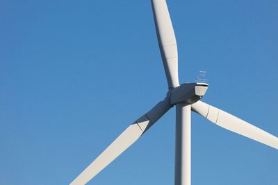 Low angle view of windmill against clear blue sky