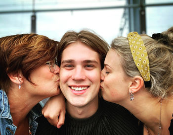 Portrait of a smiling young man, kissed bij loved ones 