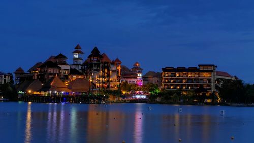 Illuminated buildings by sea at night