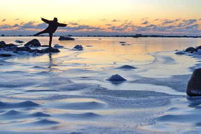 Silhouette person on beach against sky during sunset