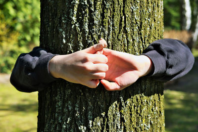 Kid hands embracing an oak tree trunk, feeling at one with nature. environmental protection concept