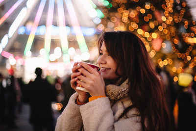 Portrait of happy teenage girl drinking mulled wine during christmas