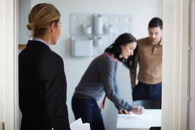 Real estate agent looking at couple signing documents of new house