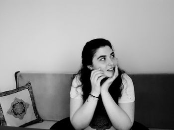 Young woman sitting on sofa against wall at home