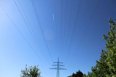Low angle view of electricity pylon against clear blue sky