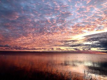 Scenic view of sea against dramatic sky during sunset