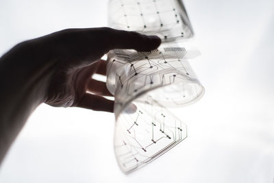 Close-up of hand holding transparent material against white background