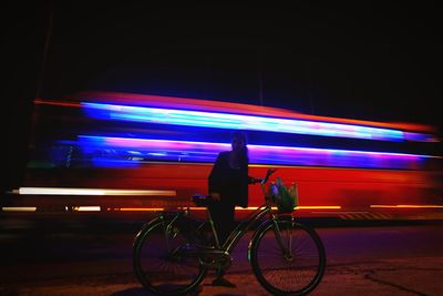 Man cycling on illuminated street at night