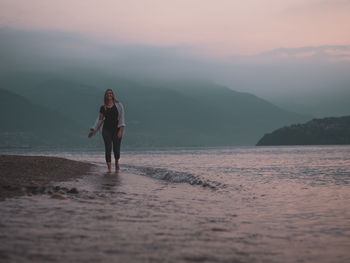 Man standing on beach against sky during sunset