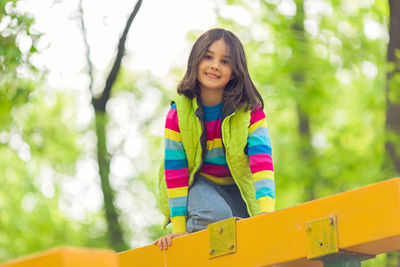 Portrait of a cute little girl on a bright wooden platform in the park in spring