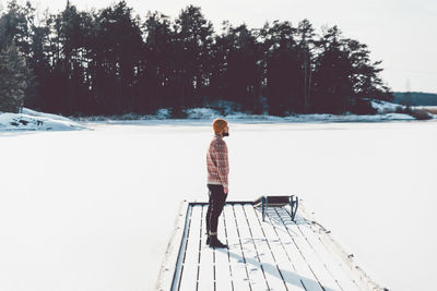 Rear view of woman standing on snow against trees