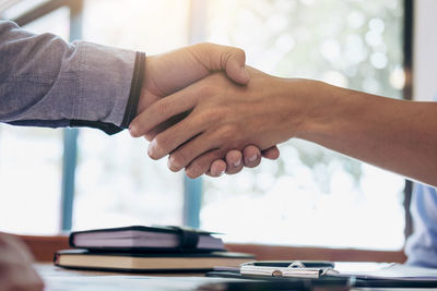 Midsection of businessman handshaking with colleague over office desk