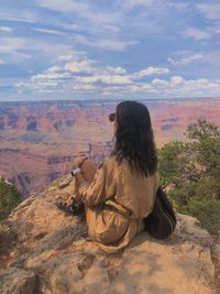 Rear view of man sitting on rock