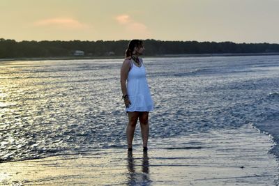 Full length of a girl standing on beach against sky