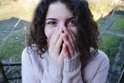 Portrait of young woman surprised woman covering mouth on field