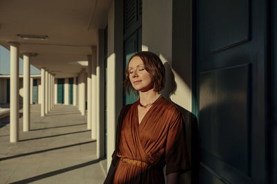 Female tourist standing with eyes closed by door in resort at deauville, france