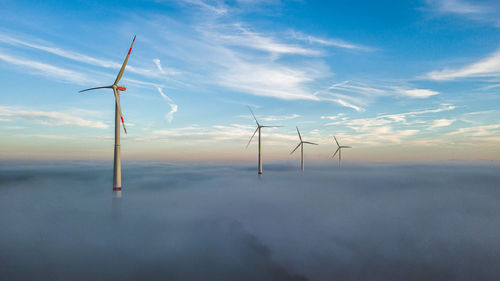 Wind turbines on landscape against sky