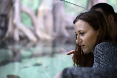 Thoughtful woman standing against trees