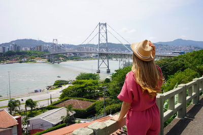 Back view of beautiful traveler girl enjoying view of hercilio luz bridge in florianopolis, brazil.