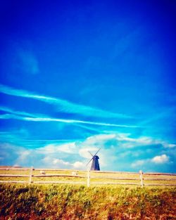 Windmill on field against blue sky