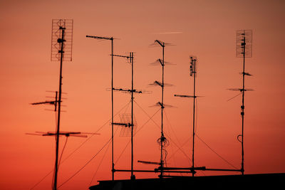 Low angle view of silhouette pole against orange sky