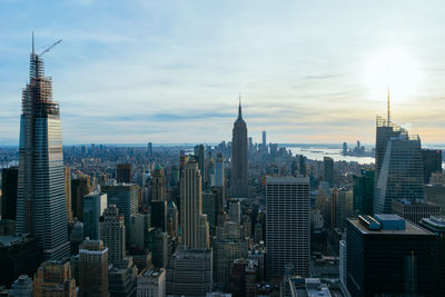 Aerial view of buildings in city against cloudy sky