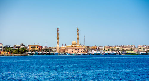 View of sea and buildings against blue sky