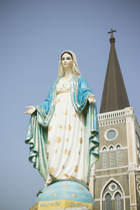 Low angle view of statue against temple against clear blue sky