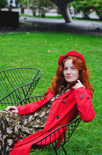 Young happy woman with red hair, freckles, beret, coat walking in autumn park, drinking coffee