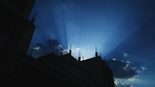 Low angle view of silhouette buildings against blue sky