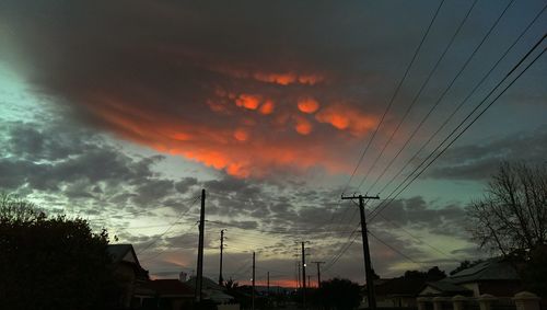 Low angle view of electricity pylon against cloudy sky